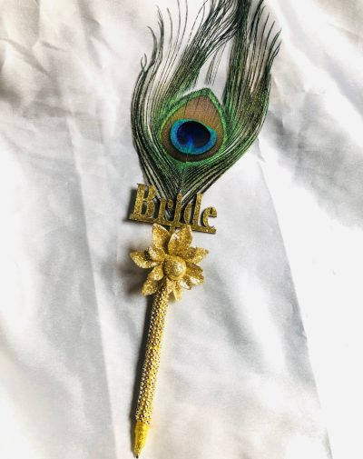 Beautiful peacock feathered Nikkah Pen For Bride, white gold colored Bride written on it. It has a gold flower on it.