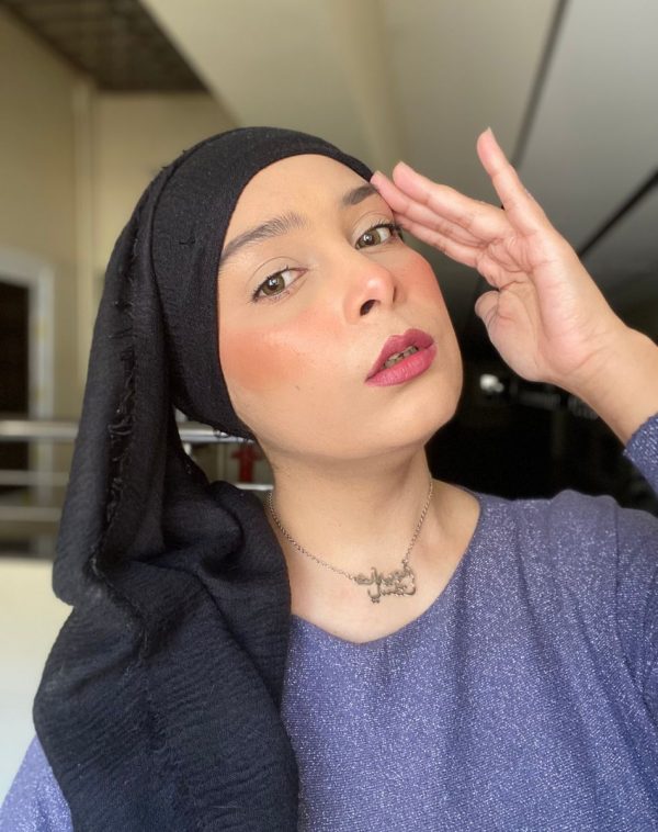 Influencer Khadija Yaseen showcases our Double Arabic Name Silver Plated Necklace while wearing a blue top and a black scarf in a captivating selfie.