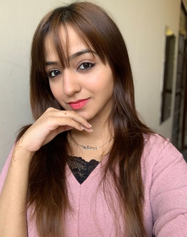 Influencer Muqaddas shines in our Single Arabic Name Silver-Plated Necklace, capturing a captivating selfie in a pink-toned setting. Her hand gently rests on her chin, showcasing the elegance of the necklace.