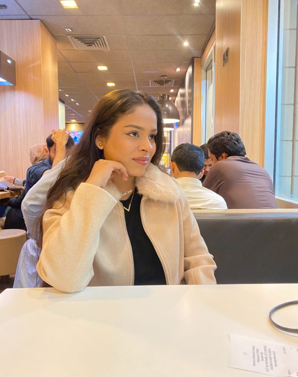 Candid shot of influencer Amna Owais wearing our Double Name Double Chain Gold-plated necklace in a restaurant, captured by someone else.