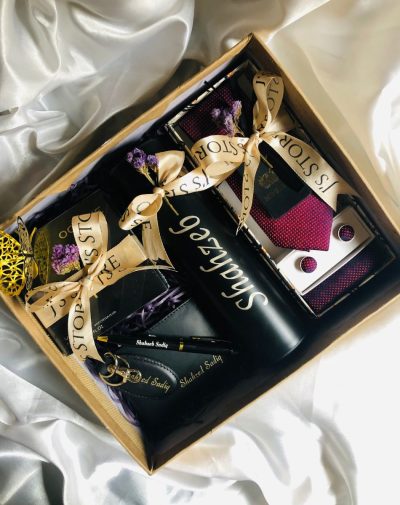 A luxurious and thoughtfully curated Charmed Anniversary Gift Box with customized name engraved wallet, keychain and pen set, temperature showing bottle, matching tie, cufflinks and pocket square, greeting card and mini cards packed in a premium gift box with brand's ribbon, perfect for gifting on various occasions