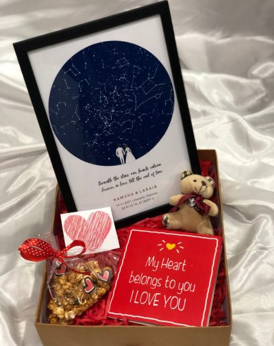 A red gift box decorated with hearts and a ribbon, with a Star Map Frame, a bag of Salted Caramel Popcorn, a cute teddy bear, and a Valentine's Day Special greeting card inside.