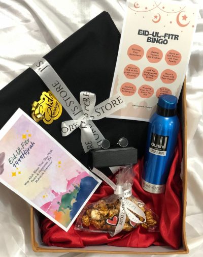 Minimally Traditional Gift Box image features a curated gift box with a branded unstitched menswear suit, Dunhill deodorant spray, marble cufflinks, bag of salted caramel popcorn, and Eid-ul-Fitr bingo game and greeting card, presented in a 10*12 inches box with ribbons, mini cards, and shredded papers.