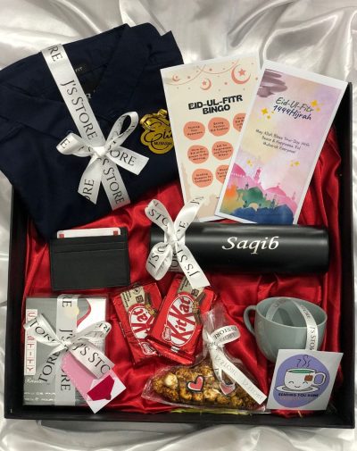 Eid Mubarak Surprise Box with ZARA Plain Casual Shirt, Rasasi Perfume, Customized Temperature Bottle, Leather Card Holder, KitKats, Salted Caramel Popcorn, Bingo Game Card, Greeting Card, Tea Cup and Flavored Tea Bags, all packed in a premium box with imported shredded papers, ribbons, and mini cards.