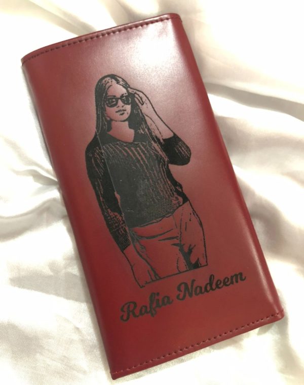 Red leather wallet with black engraved name and picture personalization, laying open to reveal compartments. Perfect for stylish storage.