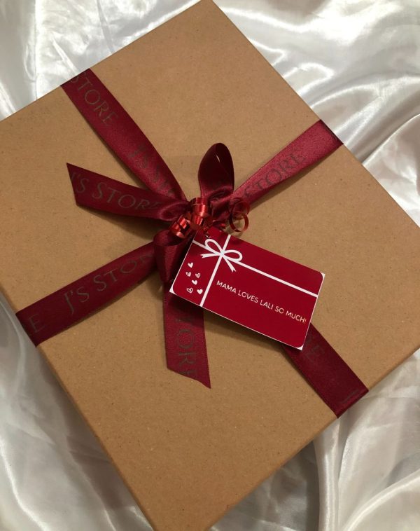 Beige gift box with white interior, wrapped in red ribbon and decorated with birthday cards, showcasing the various items inside.