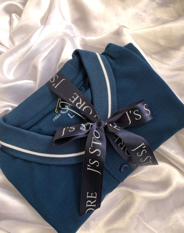 J's Store FP Polo Shirt, a classic shade of blue, elegantly nestled against a crisp white background, complete with a playful ribbon tie adding a touch of charm.
