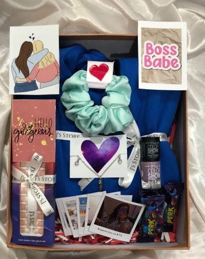 Polaroid Memories & Sweet Surprises Budget-Friendly Gift Goals is a gift box for her. It has an Electric Blue Peplum Blazer, Maybelline Color Show Nail Polish, Package of French Press-on Nails, a green scrunchie with a heart, necklace and chocolates.