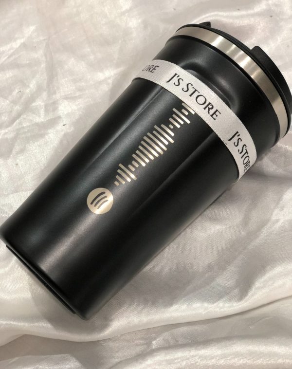 A temperature display coffee mug with J's Store ribbon on and a scannable spotify ink.