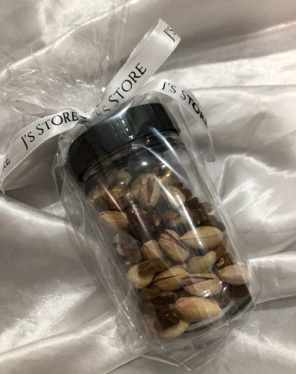 Jar of dried fruits, packed beautifully with a J's Store ribbon on the lid and is placed on a silky white background.