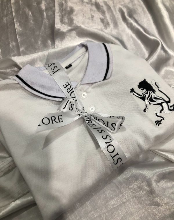 A white polo shirt, with black detailing on collar and chest. Embellished with a white J's store ribbon.