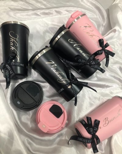 5 coffee tumblers, three black and two pink. They have decorative ribbons on and the lids have LED that shows the temperature of your beverage inside.