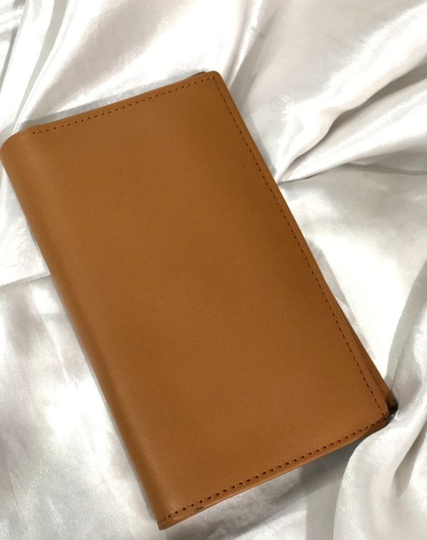 J's Store Camel Long Leather Wallet for Men. A sleek, easy to carry wallet for men. It is placed on a white satin cloth.