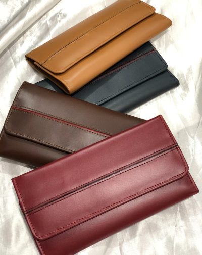 Four classic carry leather wallets for women in black, dark brown, camel, and red on a white fabric.