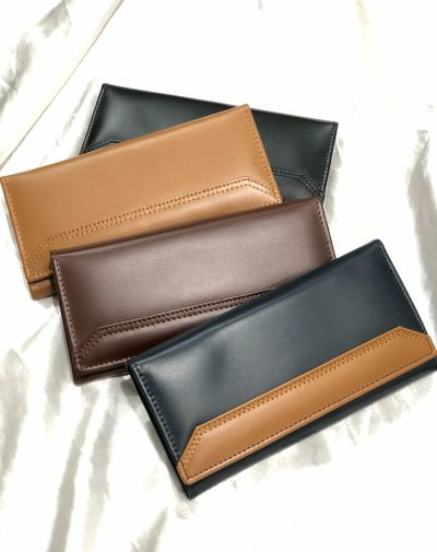 Four everyday leather wallets in black, dark brown, camel, and blue arranged on a white fabric.