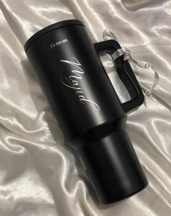Black Quencher Tumbler with the name 'Majid' engraved on it, showcasing J's Store's personalization service.