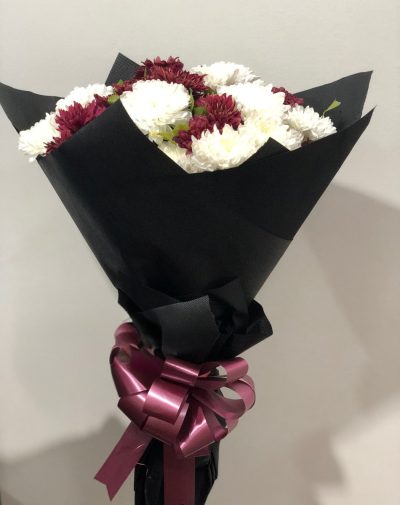 Midnight Bloom Bouquet – A sophisticated bouquet of deep burgundy and white flowers, wrapped in black paper with a maroon ribbon.