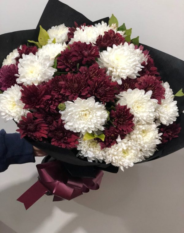 Midnight Bloom Bouquet Close-up. A sophisticated bouquet of deep burgundy and white flowers, wrapped in black paper with a maroon ribbon.