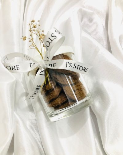 Cookie Jar from J’s Store. Small glass jar filled with dark chocolate cookies, tied with a white ribbon and dried flowers.