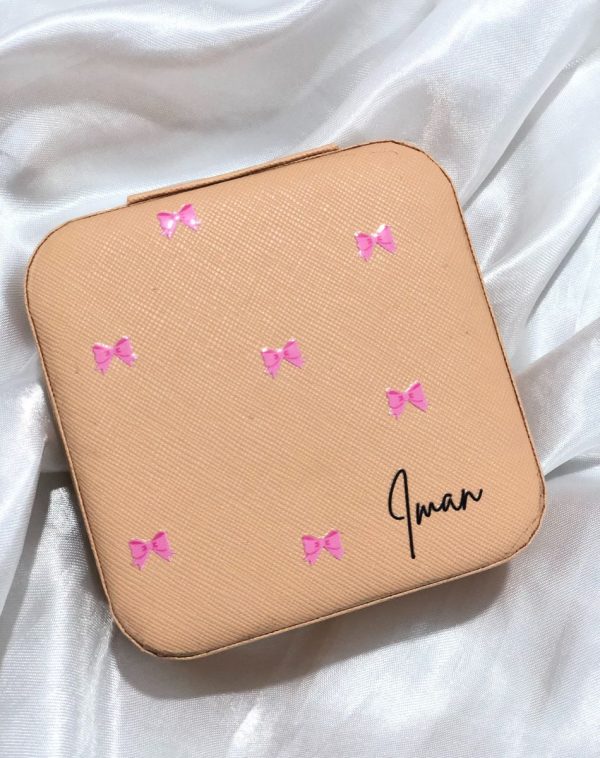 Customized Jewelry Organizer in a nude pink leather finish with a bow pattern and the custom name "Iman."