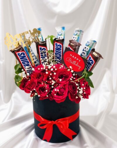 The Sweet Indulgence Bucket chocolate bouquet featuring red roses Snickers and Bounty bars in a black box from J's Store